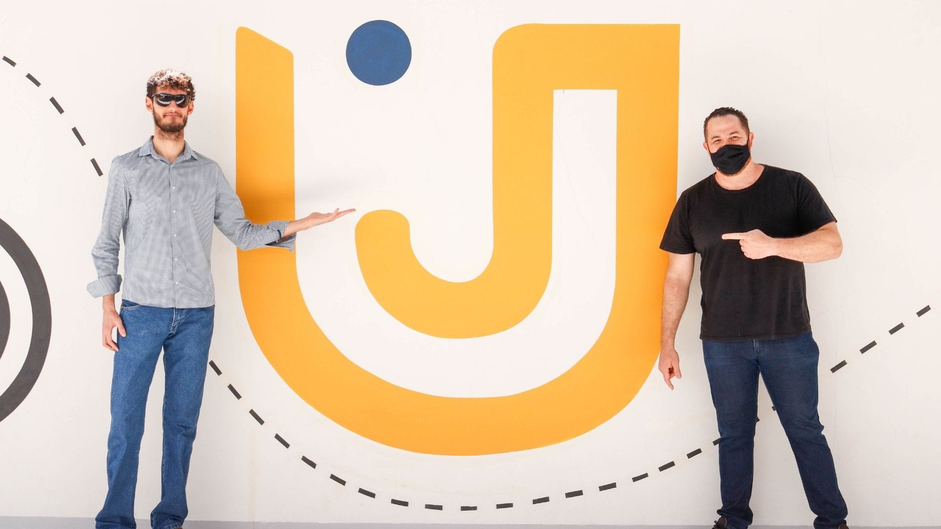 A imagem mostra o alumni e seu sócio, que participaram do evento QQSU, com o logo do Grupo UniEduK.