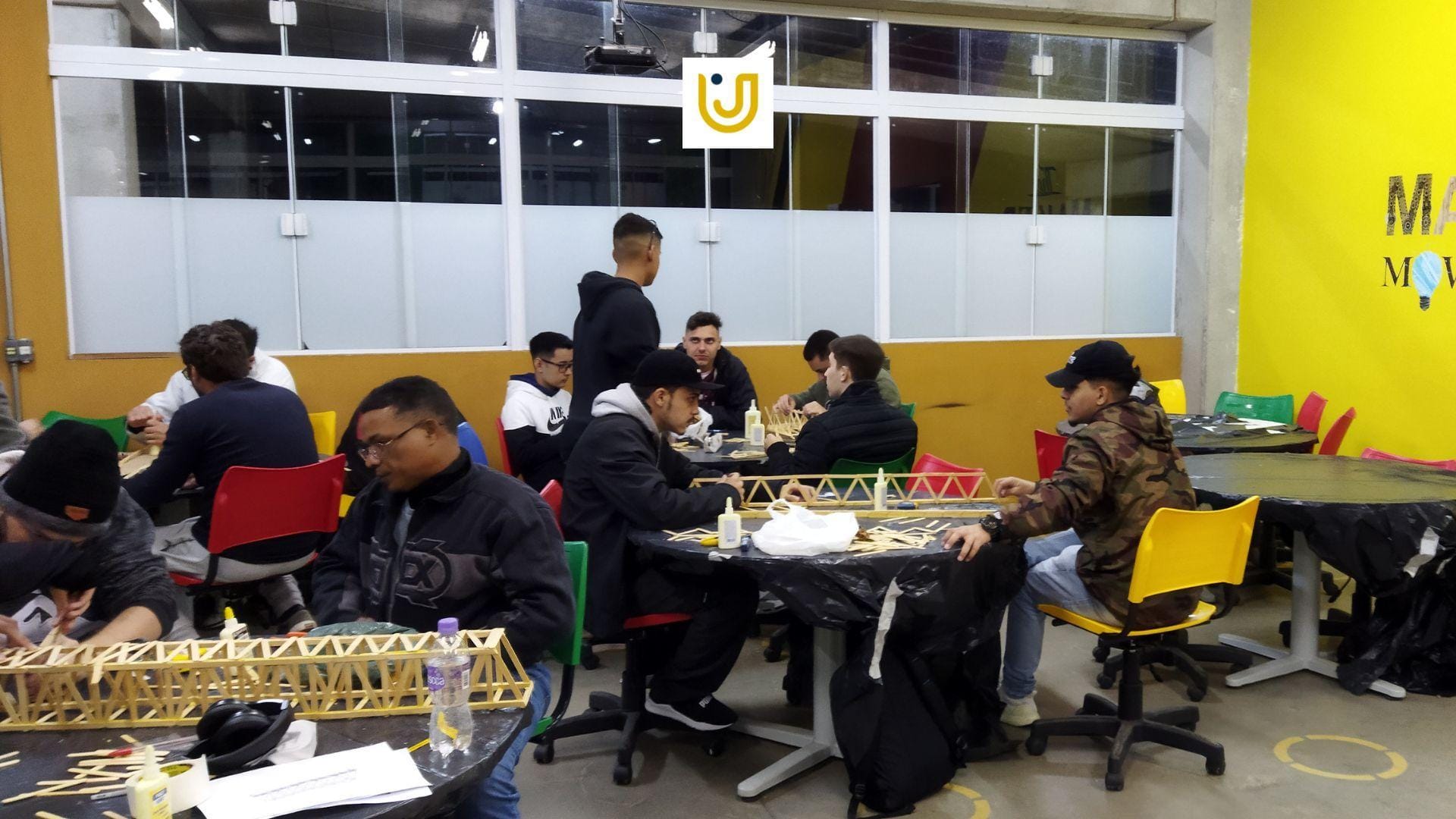 A imagem mostra os alunos de Engenharia do Grupo UniEduK durante a aula com construção de pontes, sobre resistência de materiais.